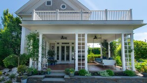 A two-story house with a covered porch, a front door, and a staircase leading to the upper level. - Luxurious Estate, Private Heated pool! (West Harwich)