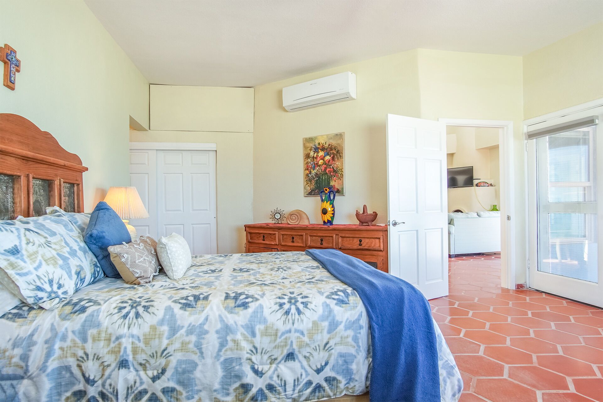 Un dormitorio con una cama, un tocador, un cuadro y una puerta que da a una cocina.