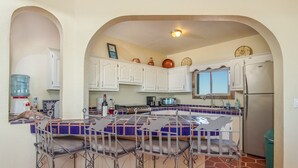 Una cocina con armarios blancos, una isla con azulejos azules y un refrigerador de acero inoxidable.