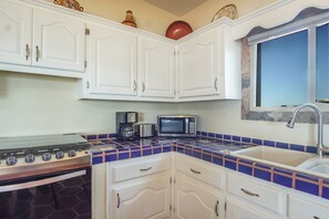 Compact kitchen with gas stove, coffee maker, and microwave, featuring a functional layout and ample storage.