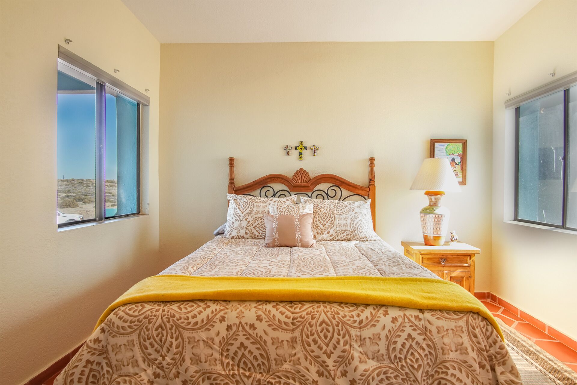 Une chambre à coucher avec un lit, une table de chevet, une lampe et une fenêtre donnant sur un paysage désertique.