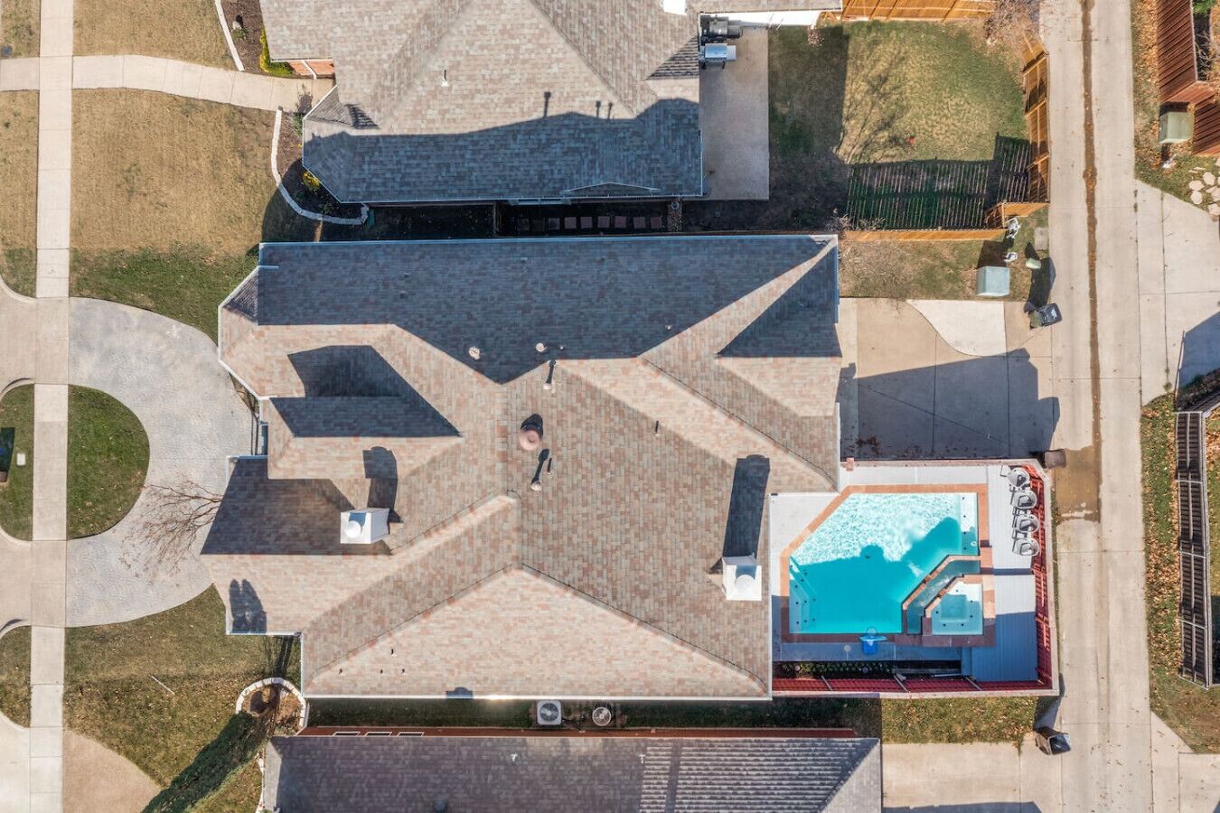 An aerial view of a building with a swimming pool, a covered patio, and a landscaped area with pathways.