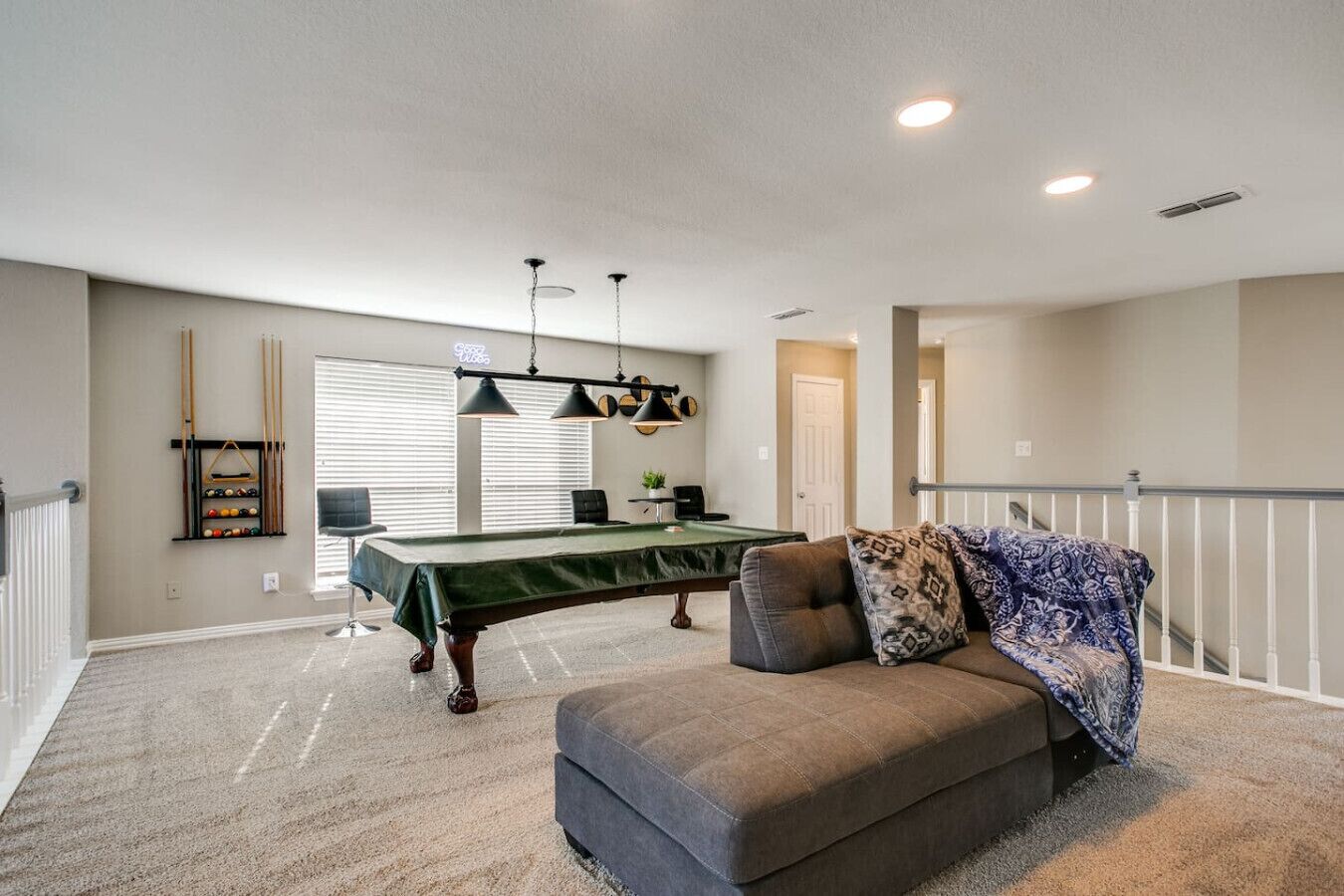 Ein geräumiges Zimmer mit Billardtisch, einer Couch und einer Treppe.