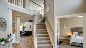 A spacious living area with a staircase leading to a bedroom. - Luxury 5 Bedroom, 3.5 Bathroom Pool Hot Tub (Plano)