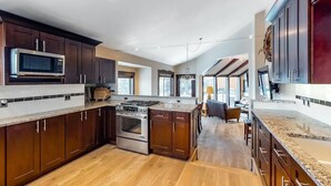 A modern kitchen with dark wood cabinets, stainless steel appliances, and a central island.