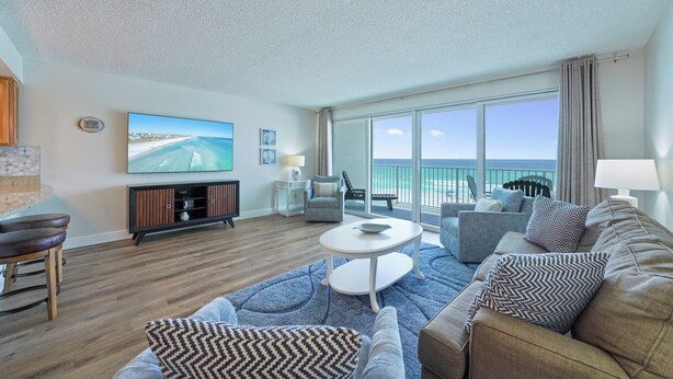 A modern living room with a large TV, comfortable seating, a coffee table, and a view of the ocean through large windows. - Amazing Gulf Front Views at Cabana Club 307 (Destin)