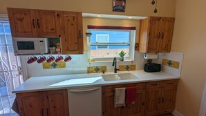 Una cocina con armarios de madera, microondas, lavabo y ventana con vistas.