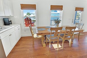 A dining area with a wooden table and chairs, white cabinets, and a coffee maker. - RAY'S ROOST WITH 6BD, 2 FULL KITCHENS, 2 LIVING AREAS, PERFECT FOR MULTI FAMILIES! (Mexico Beach)
