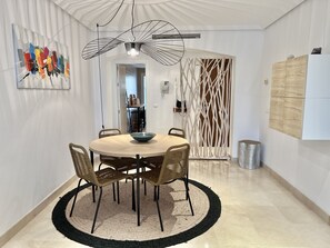 Ett modernt matområde med ett runt bord, flätade stolar, en dekorativ matta och en unik taklampa.
