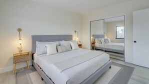 Ein modernes Schlafzimmer mit einem großen Bett, Nachttischen, einem Spiegel und einem Kleiderschrank.