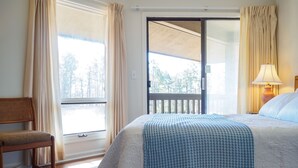 Ein Hotelzimmer mit Bett, Sessel, Lampe und Blick ins Freie durch eine Schiebetür.