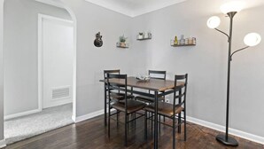 A dining area with a wooden table and chairs, a floor lamp, and wall-mounted shelves with decorative items. - Rock n Roll! DT 2bd home! Walk to beach, bars&more (Port Sanilac)