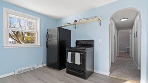 A kitchen with a refrigerator, stove, and oven. There is a window and a hallway leading to another room. - Rock n Roll! DT 2bd home! Walk to beach, bars&more (Port Sanilac)