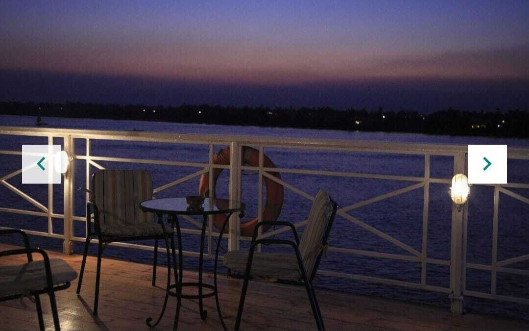 Une terrasse avec des chaises et des tables donnant sur une étendue d’eau au crépuscule.