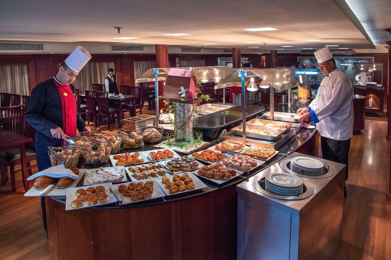 A buffet setup with various food items and two chefs preparing food.