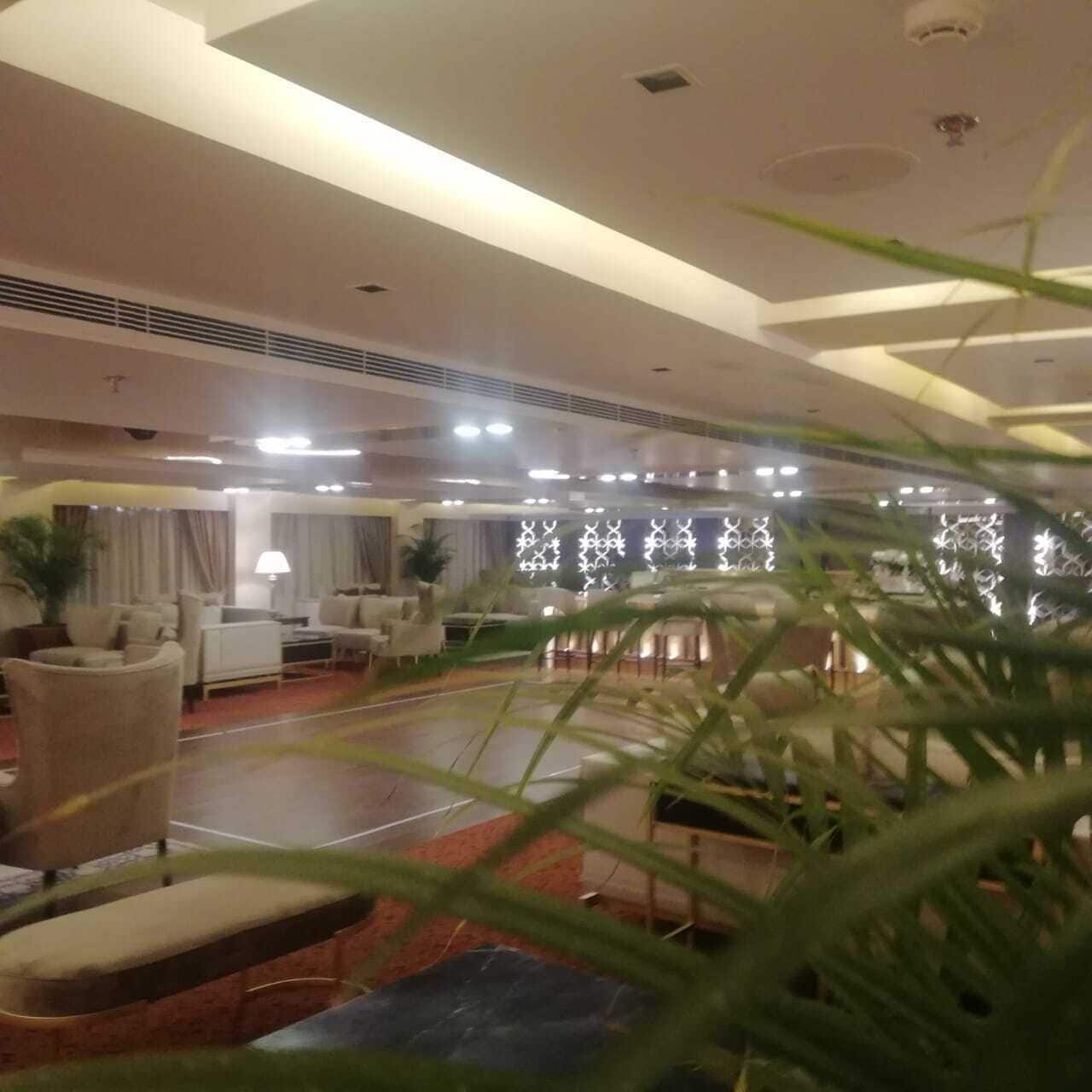 A hotel lobby with seating areas, a reception desk, and decorative lighting.