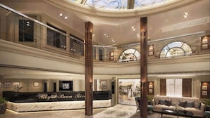 Un amplio vestíbulo con una recepción identificada como "Royal Beau River", un techo alto con tragaluces y una zona de estar con sofá y mesa de centro.