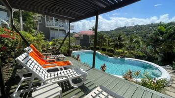 Relax by the serene pool surrounded by lush greenery and palm trees.