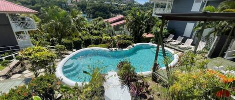 A swimming pool surrounded by lush greenery and a view of a hilly landscape.