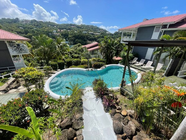 A swimming pool surrounded by lush greenery and a view of a hilly landscape.