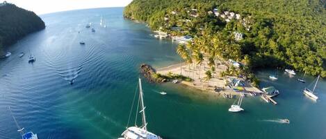 Une zone côtière avec des bateaux, un port de plaisance et une colline parsemée de bâtiments.