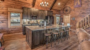 Una cucina in stile rustico con pareti in legno, un'isola grande con sgabelli da bar e un lampadario.