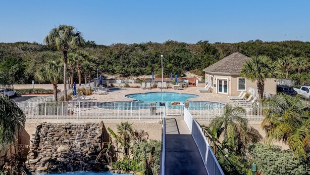 A resort with a central pool, lounge chairs, and a small building.