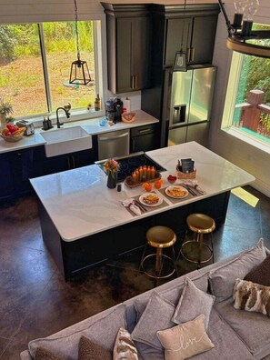 Una cocina moderna con una isla central, taburetes de bar y un comedor.