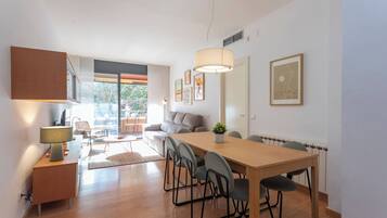 Een moderne keuken met houten kastjes, een eettafel met stoelen, een bank en een groot raam.