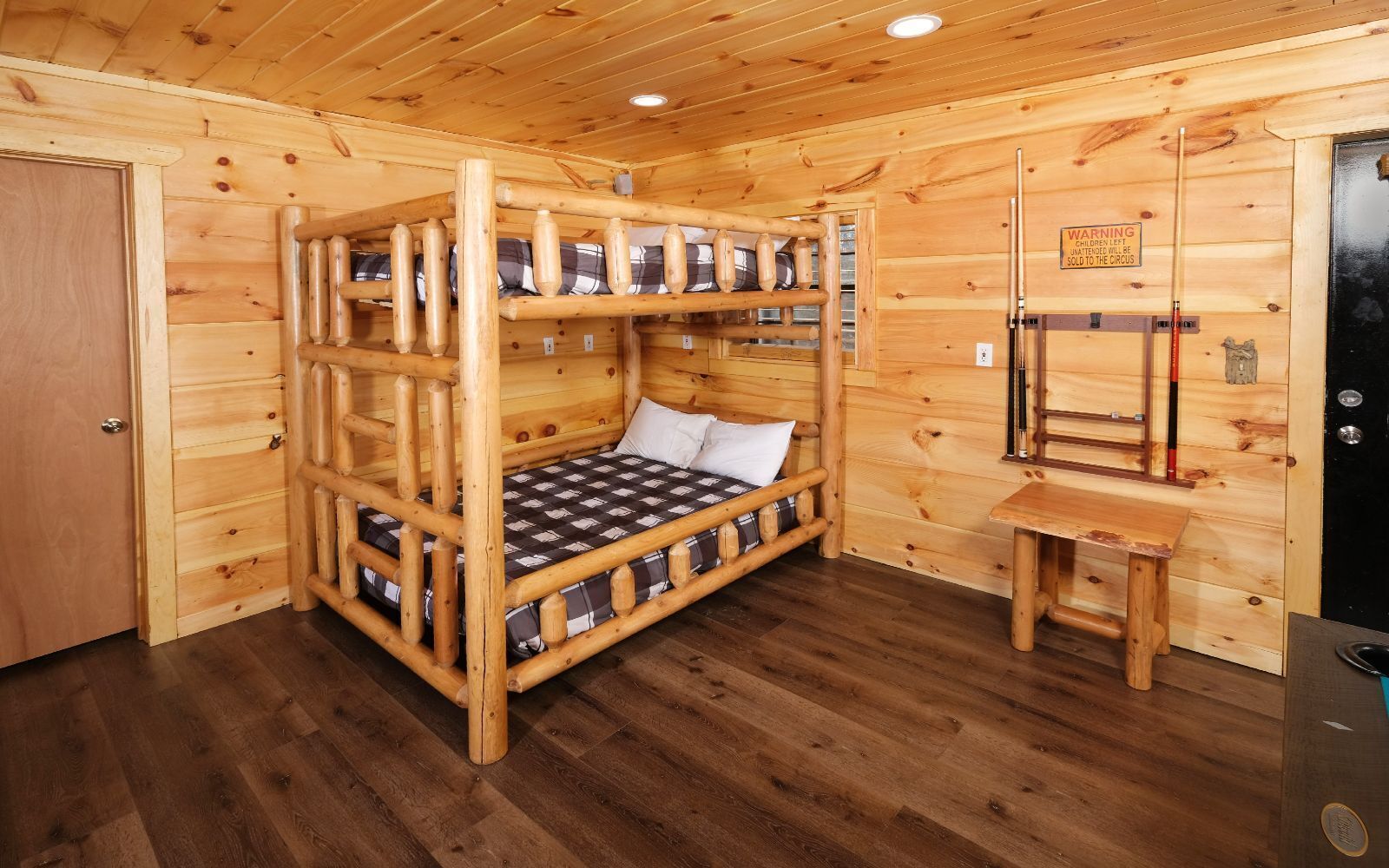 A wooden cabin room with bunk beds, a small table, and a refrigerator.