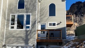 Ein zweistöckiges Haus mit Garage, Balkon und einer Steinmauer.
