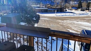 Eine Terrasse mit Blick auf eine verschneite Landschaft, Berge und ein kleines Gebäude.