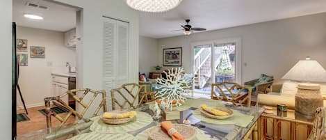 A dining area with a glass table, wicker chairs, and a ceiling fan.