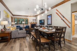 A dining area with a wooden table set for four, surrounded by chairs. - Steps to Gondolas + Hot Tub & Heated Pool - 4BR/3BA - EZCancel (Steamboat Springs)