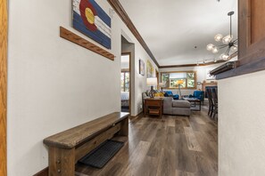 A hallway leading to a living area with a bench, a lamp, and a sofa. - *Summer Sale* Snow Flower 204 - Hot Tub & Heated Pool - Steps to Gondolas Square (Steamboat Springs)