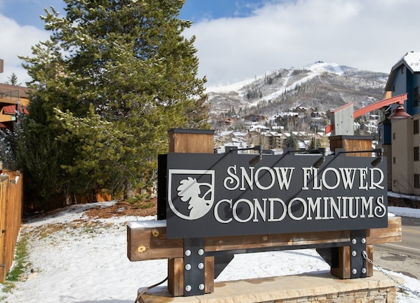 Señal de Snow Flower Condominiums, con una vista de montaña al fondo.