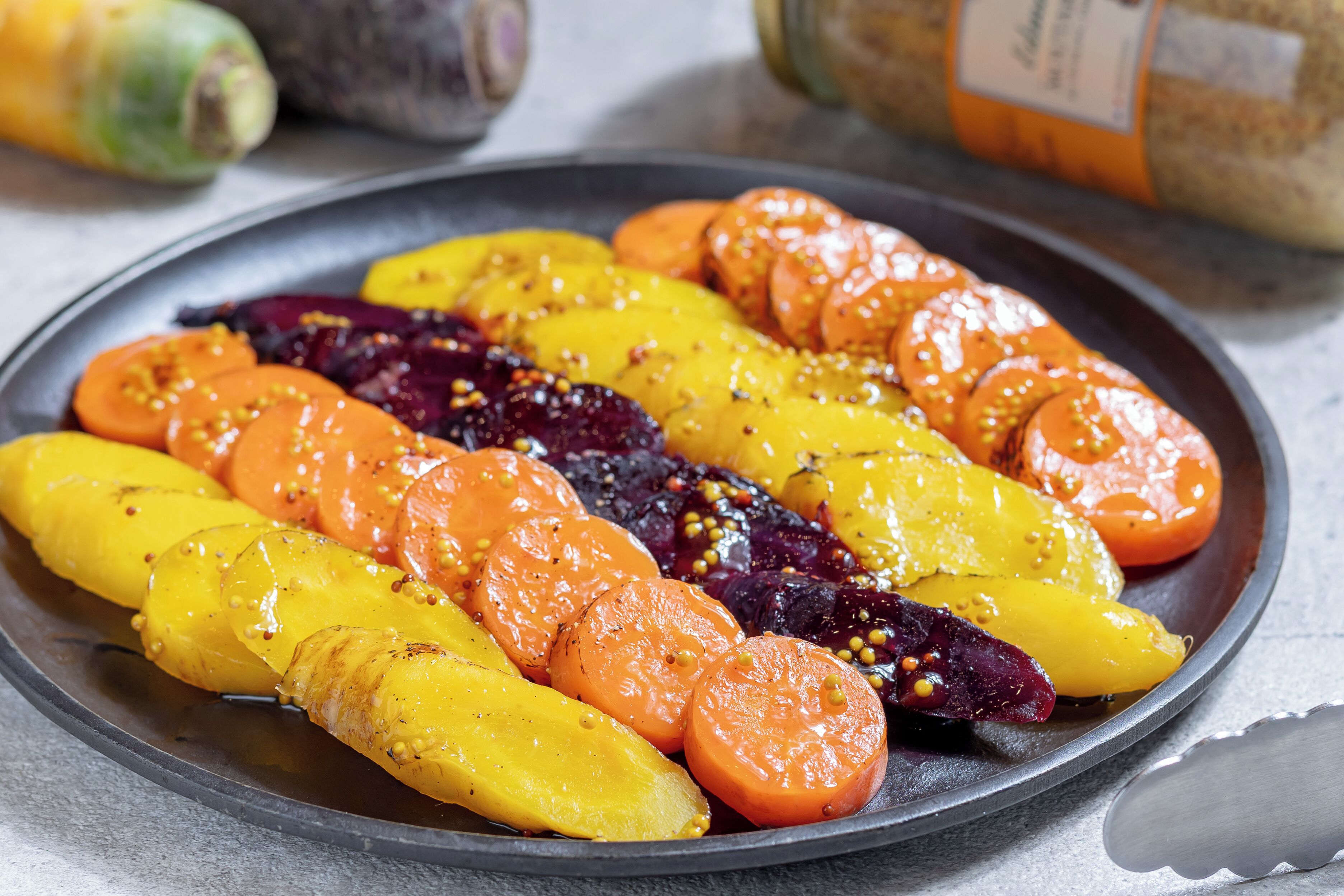 Une assiette de légumes rôtis, notamment des carottes, des betteraves et des courges.