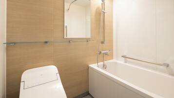 Un baño moderno con inodoro, repisa de vidrio, espejo y bañera.