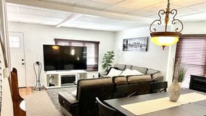A living room with a sofa, TV, and dining area. - Welcome to the Fort. Walking Distance to Niagara Falls. (Niagara Falls)