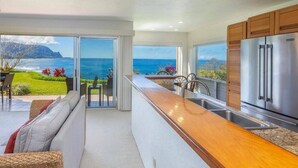 Uma cozinha moderna com vista para o oceano, bancada de madeira e eletrodomésticos de aço inoxidável.