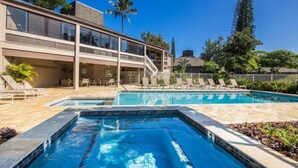 Um hotel com área de piscina, incluindo uma piscina retangular e uma área de estar com espreguiçadeiras.