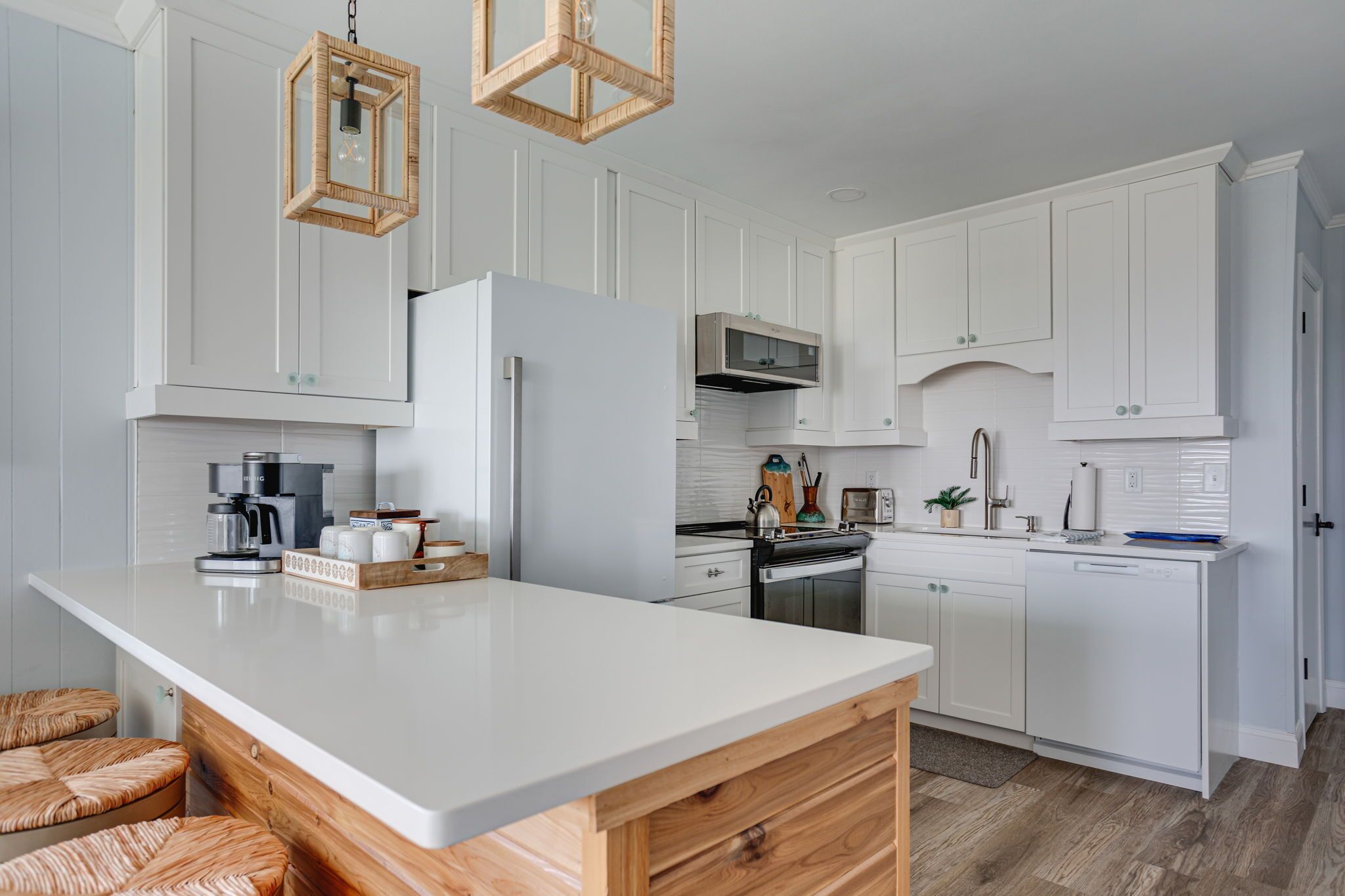 A modern kitchen with white cabinetry, a large island, and a hanging light fixture.
