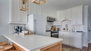 A modern kitchen with white cabinetry, a large island, and a hanging light fixture.
