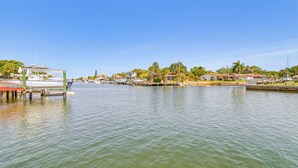 Un port de plaisance avec des bateaux amarrés, un ciel dégagé et des immeubles résidentiels le long de la rive.
