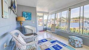 Une pièce avec vue sur un plan d’eau, des meubles en osier, un tapis à motifs et une décoration sur le thème de la marine.