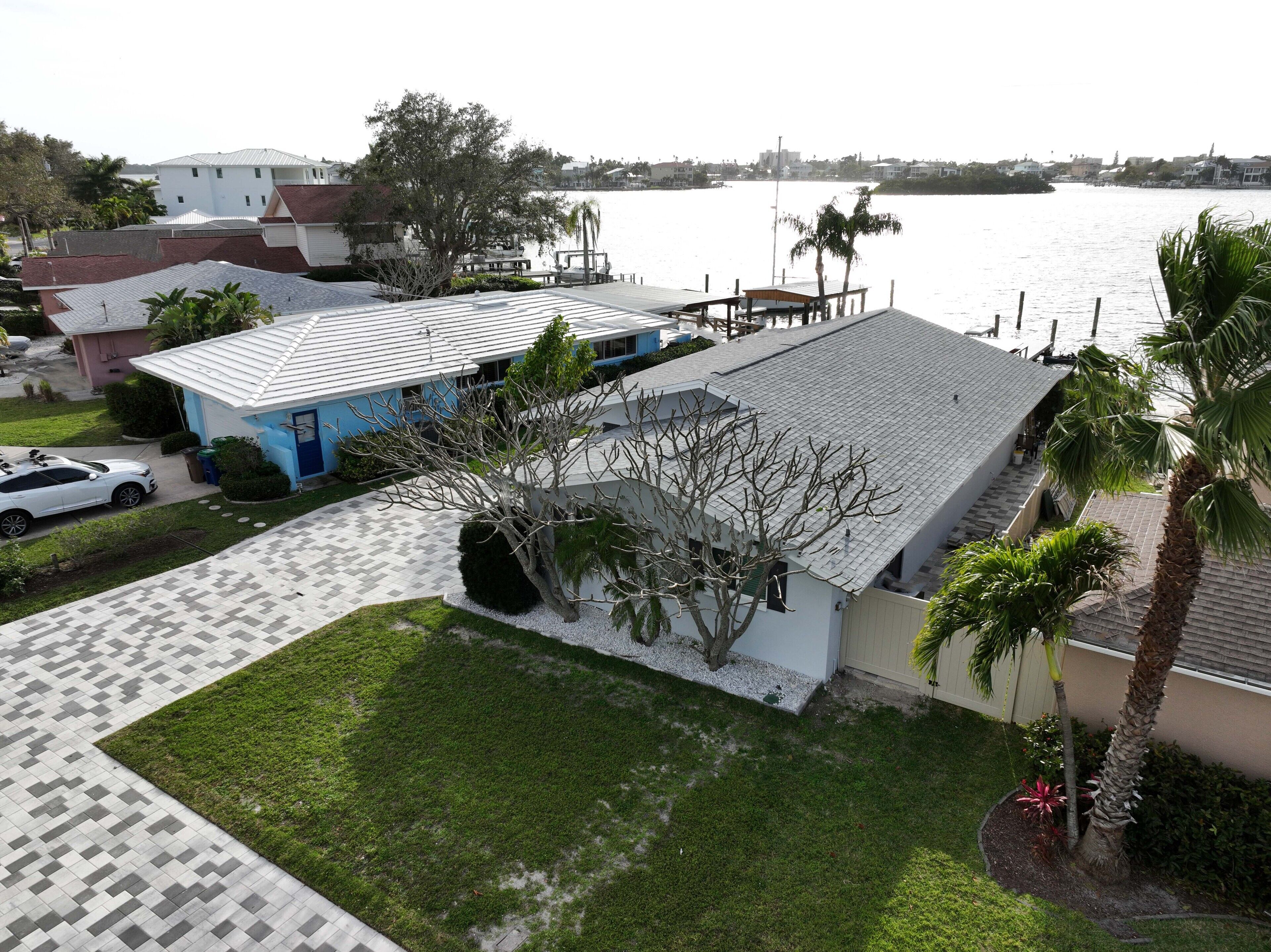 Una propiedad residencial con entrada pavimentada, una casa azul y vista al agua.