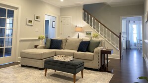 A living room with a sectional sofa, a coffee table, a ceiling fan, and a staircase leading to another level. - 4 bedroom Masters Rental 5 miles from Augusta National (Martinez)