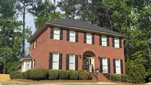 A two-story brick house with a central entrance, a front porch, and a well-maintained lawn. - 4 bedroom Masters Rental 5 miles from Augusta National (Martinez)