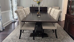 A dining room with a dark wooden table, upholstered chairs, a chandelier, and a cabinet. - 4 bedroom Masters Rental 5 miles from Augusta National (Martinez)