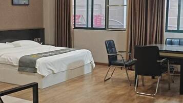 Una habitación de hotel con cama, escritorio, silla y ventana con cortinas.
